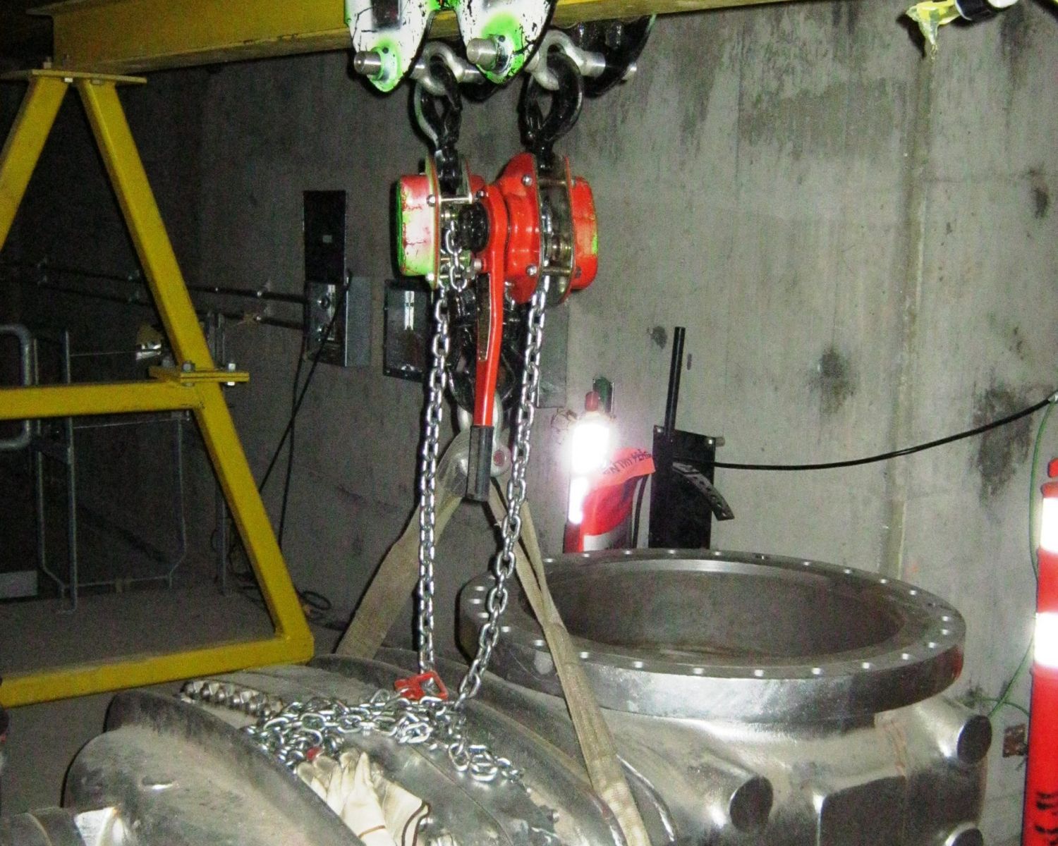 Large stainless valve rigged with chain hoists